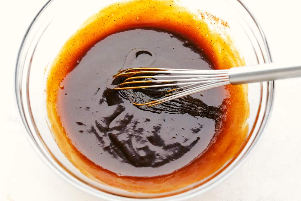 Barbecue sauce with a whisk in a clear bowl.