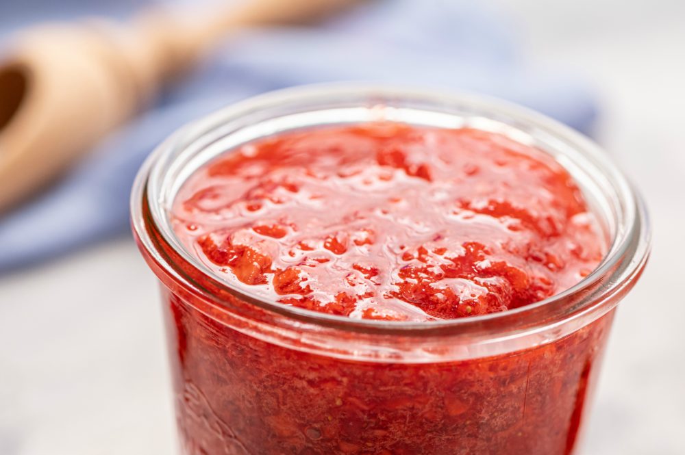 Upclose photo of the strawberry jam in a glass jar. 