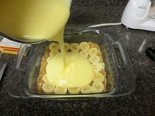 Cream being poured over the sliced bananas and Nilla Wafer base. 
