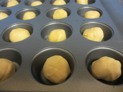 Balls of dough in a muffin tin. 