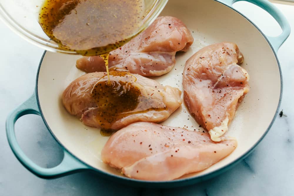 Pechugas de pollo en una sartén glaseadas con los ingredientes batidos. 