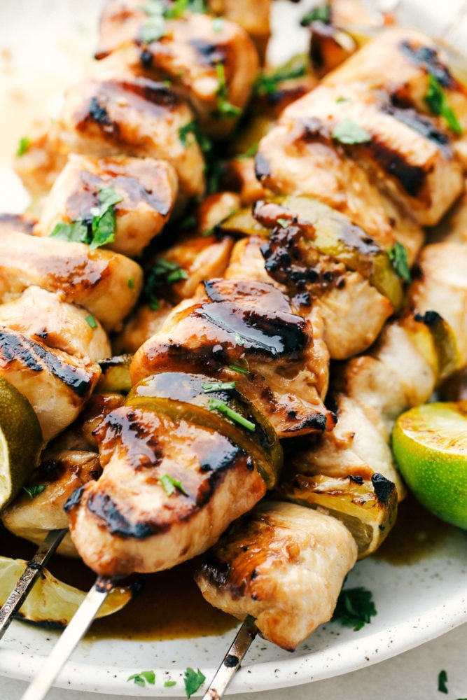 Grilled Key Lime Chicken on skewers on a white plate.