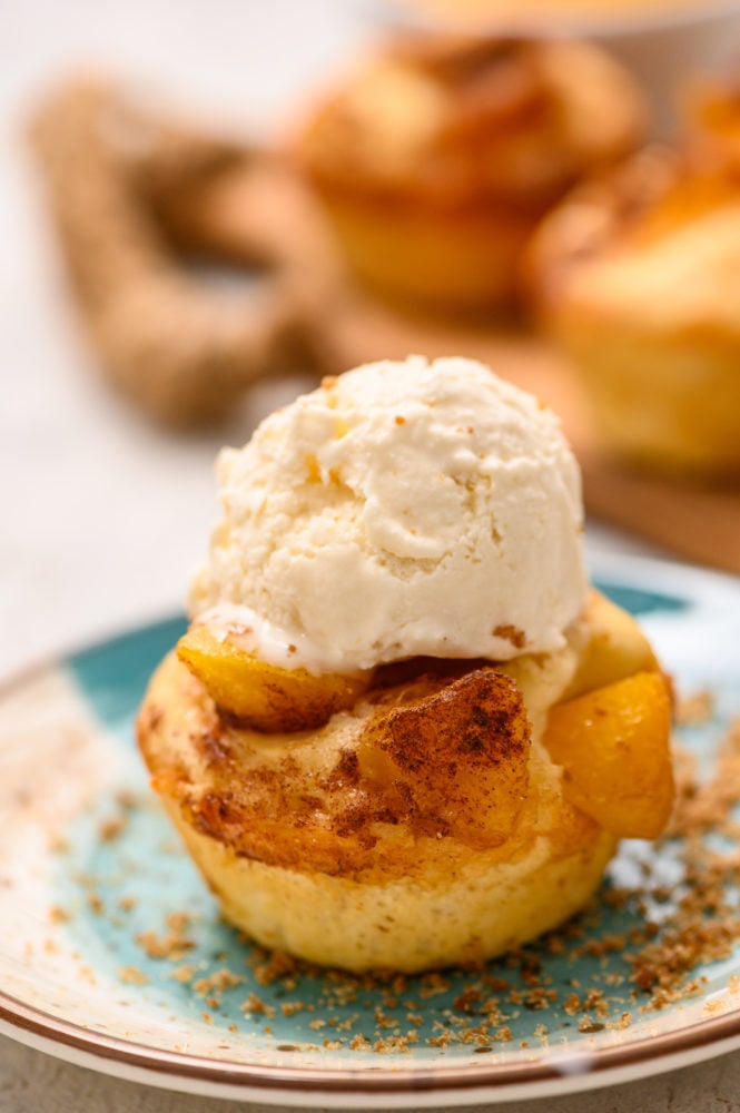 Mini peach cobbler on a plate with a scoop of vanilla on top. 