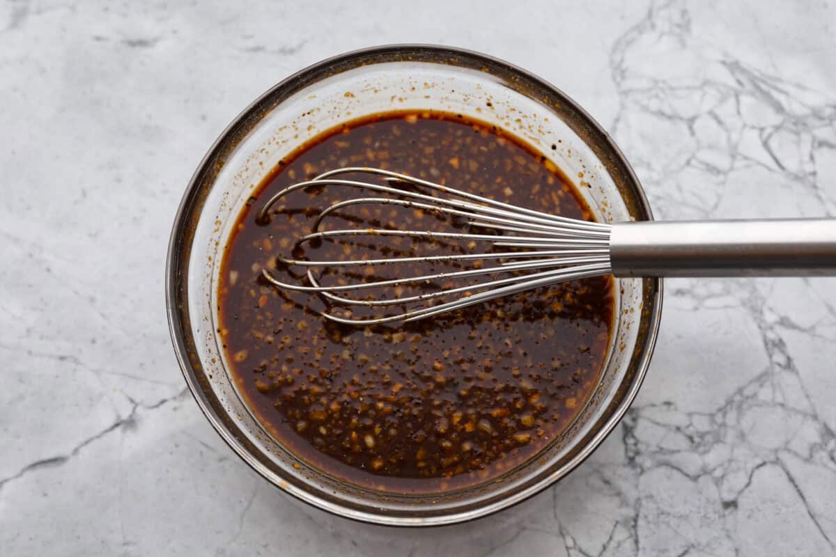 Overhead shot of sauce ingredients whisked together in a glass bowl. 