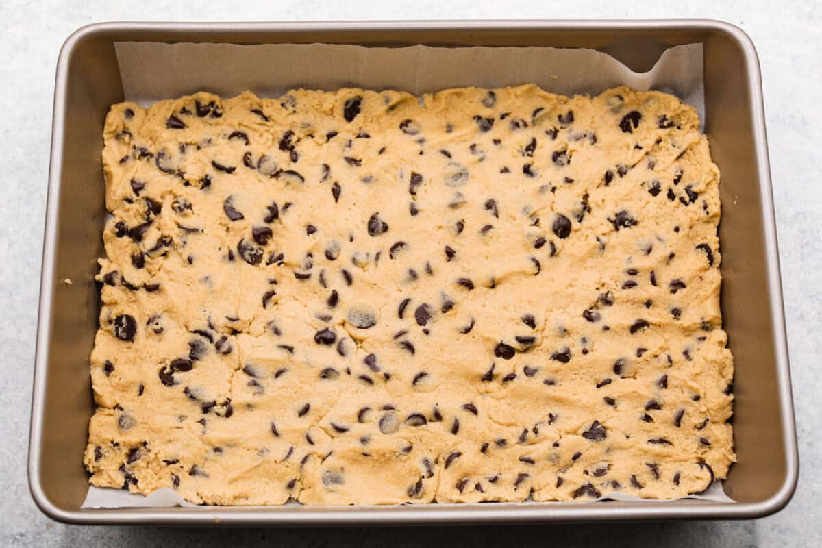 Overhead shot of brownie mixture pressed into the bottom of a pan. 