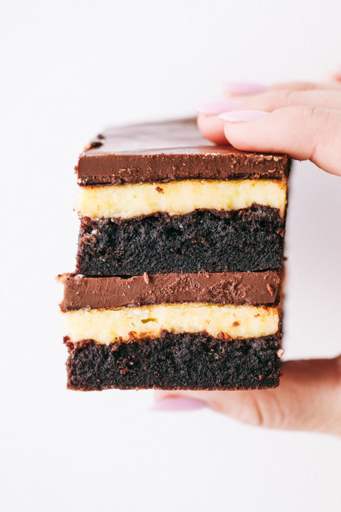 Zwei übereinander gestapelte Hershey's-Schokoladen-Käsekuchen-Brownies werden in die Luft gehalten. 