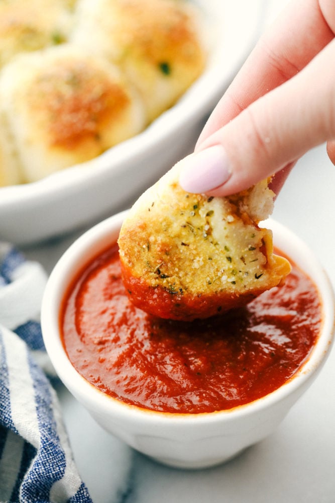 A pizza bite being dipped in marinara sauce. 