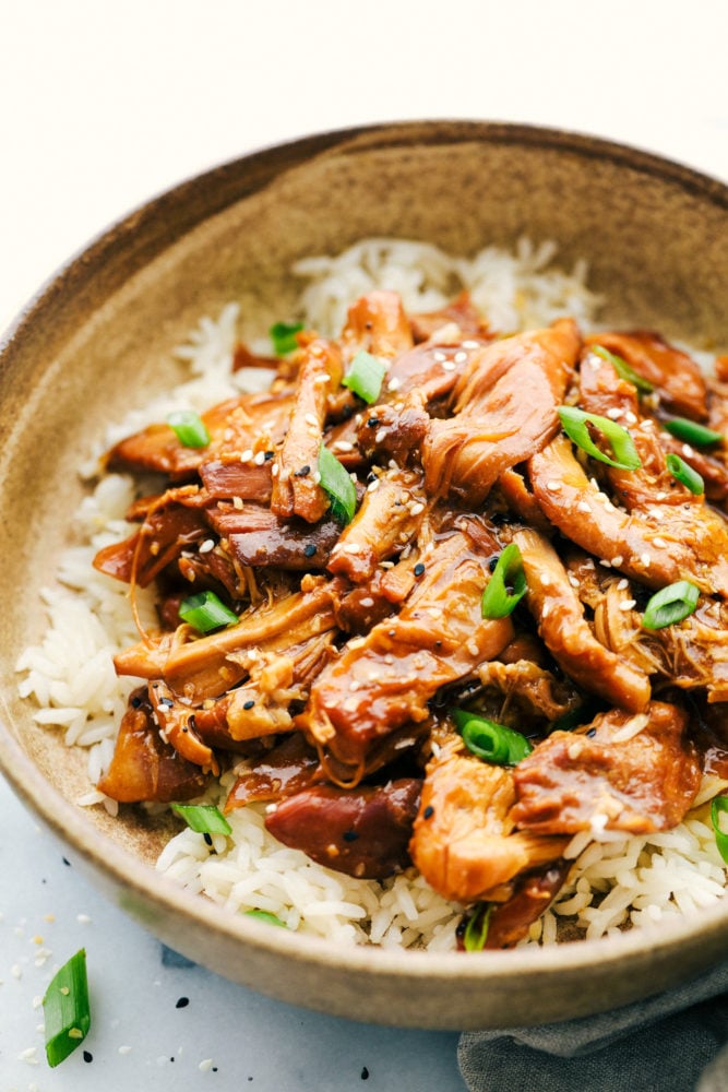 Honey garlic chicken in a bowl with rice and garnished with scallions. 