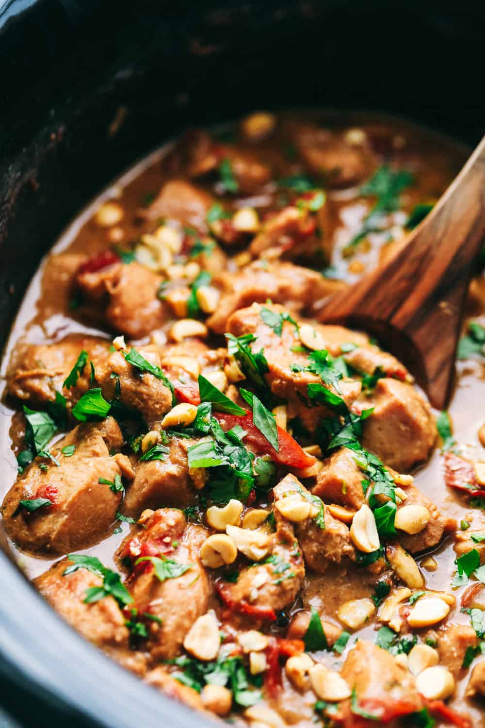 Slow cooker Thai Peanut Chicken being stirred in a pot.