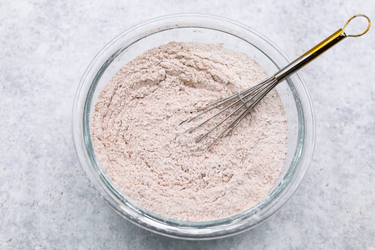 Overhead shot of dry ingredients whisked together in a glass bowl. 