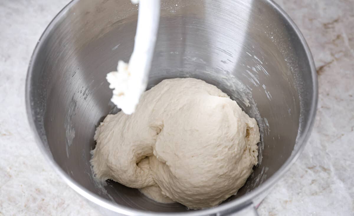 Overhead shot of dough ball in the bottom of a stand mixer bowl. 