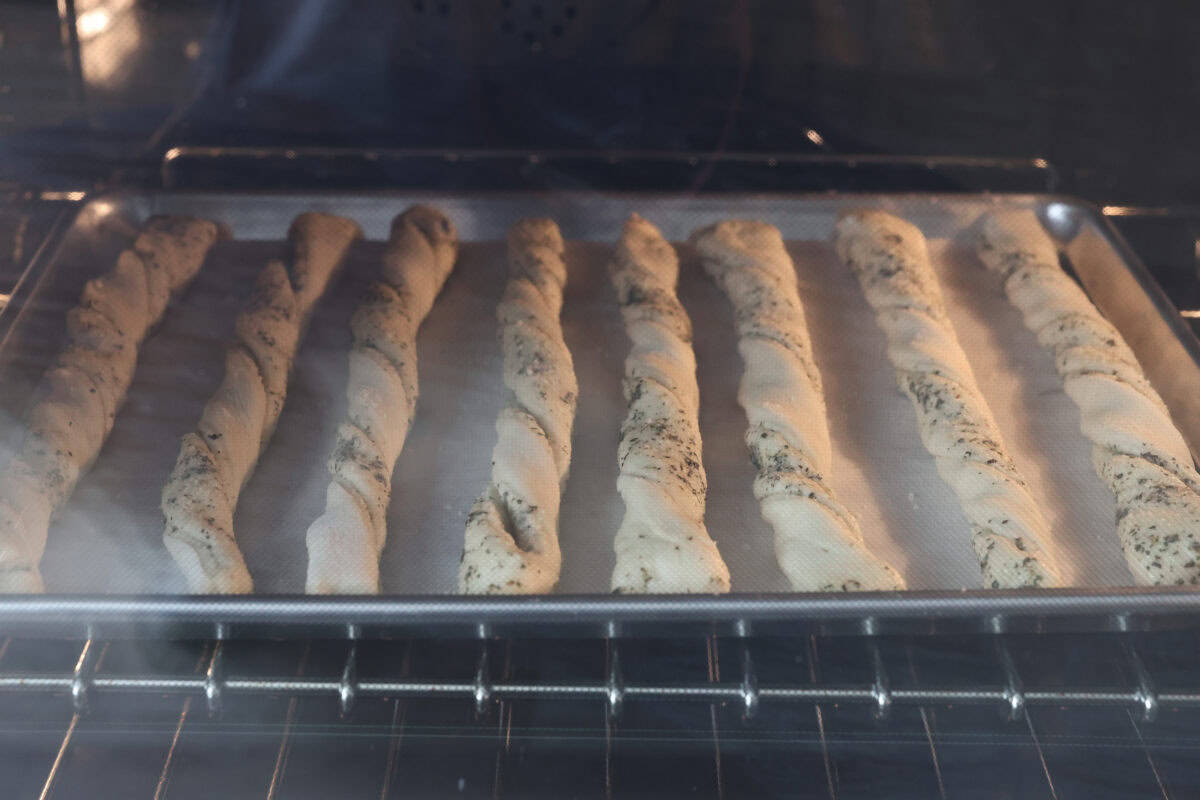 View of homemade breadtwists on a baking sheet in the oven.