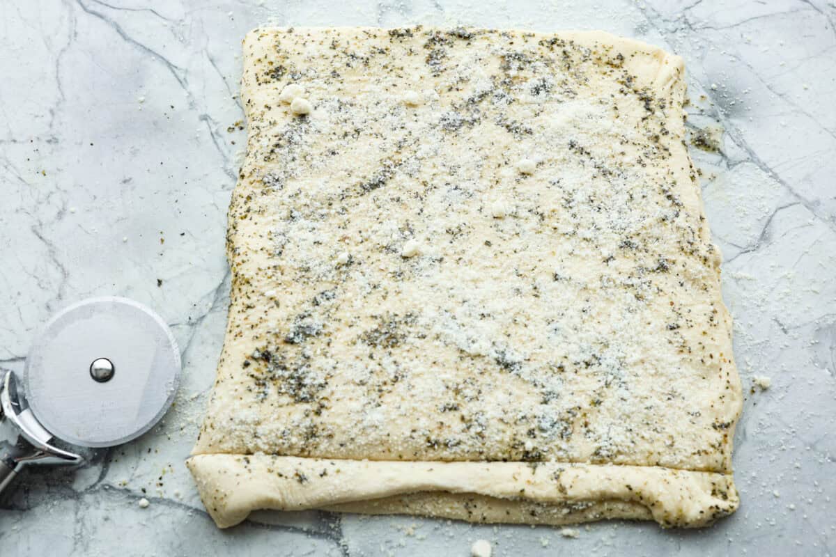 Overhead shot of homemade breadtwists dough folded in half with garlic butter and cheese spread over the top.