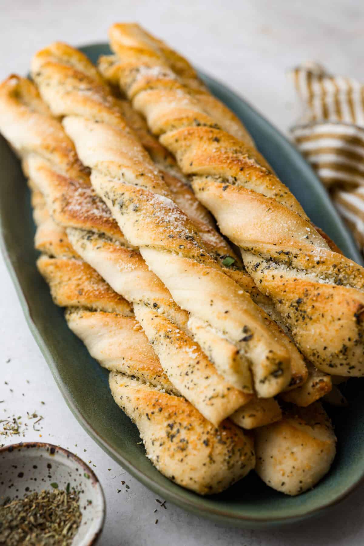 Angle shot of homemade breadtwists stacked on a plate. 