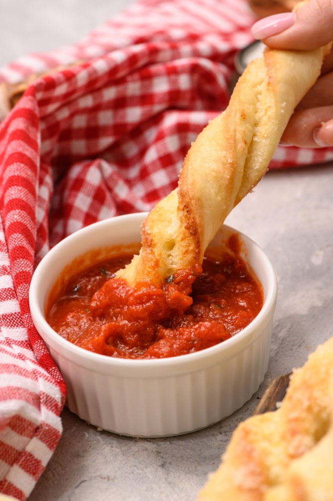 Dipping a breadtwist into red sauce.