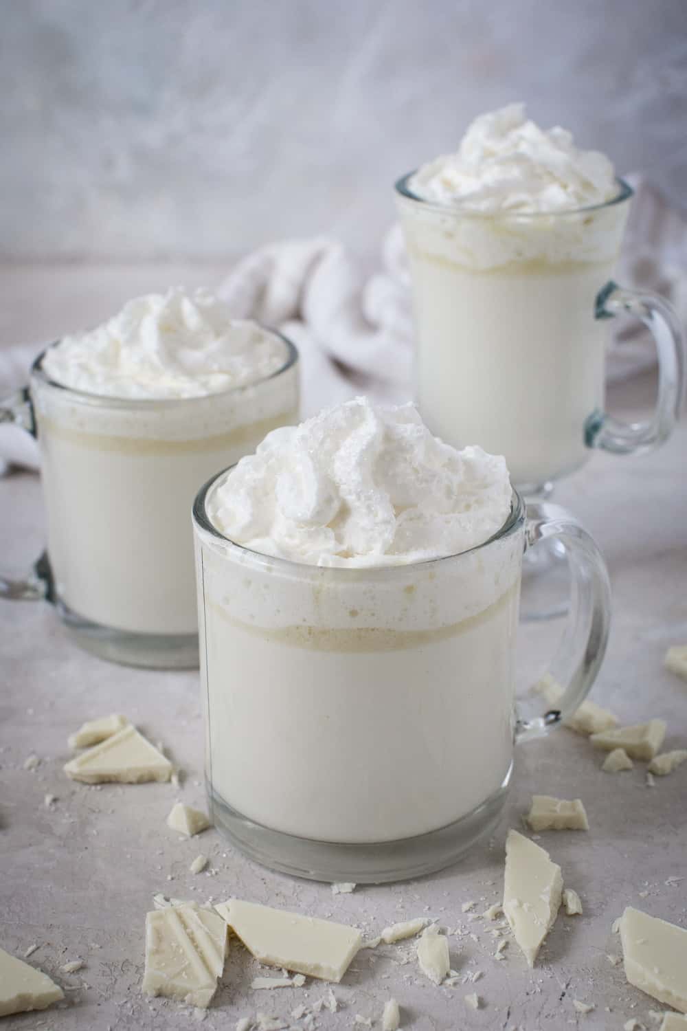 White hot chocolate in glasses with whipped topping.