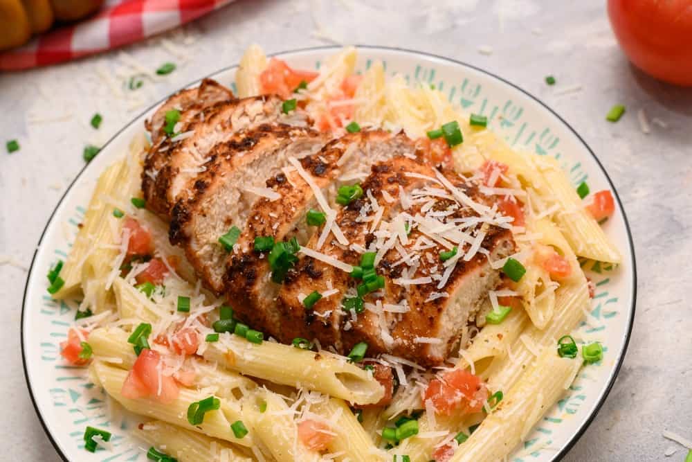 Cajun chicken pasta on a plate garnished with shredded parmesan. 