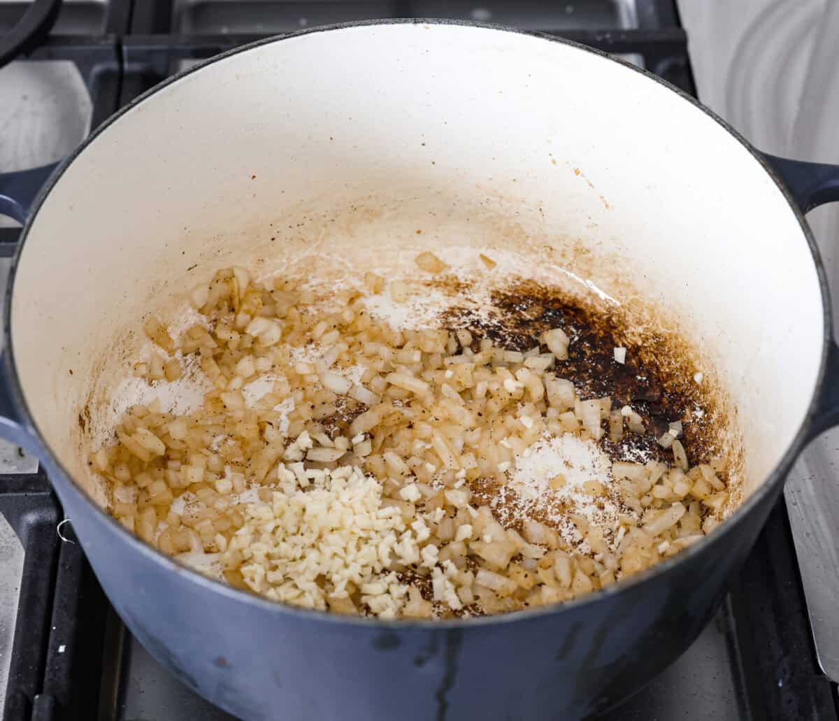 Angle shot of onions and garlic cooking in a large pot. 