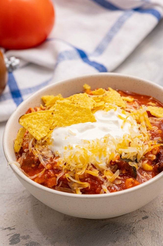 Skinny taco soup in a white bowl garnished with chips and cheese. 