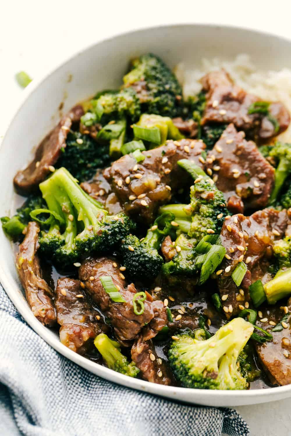 Beef and broccoli over rice in a white bowl. 