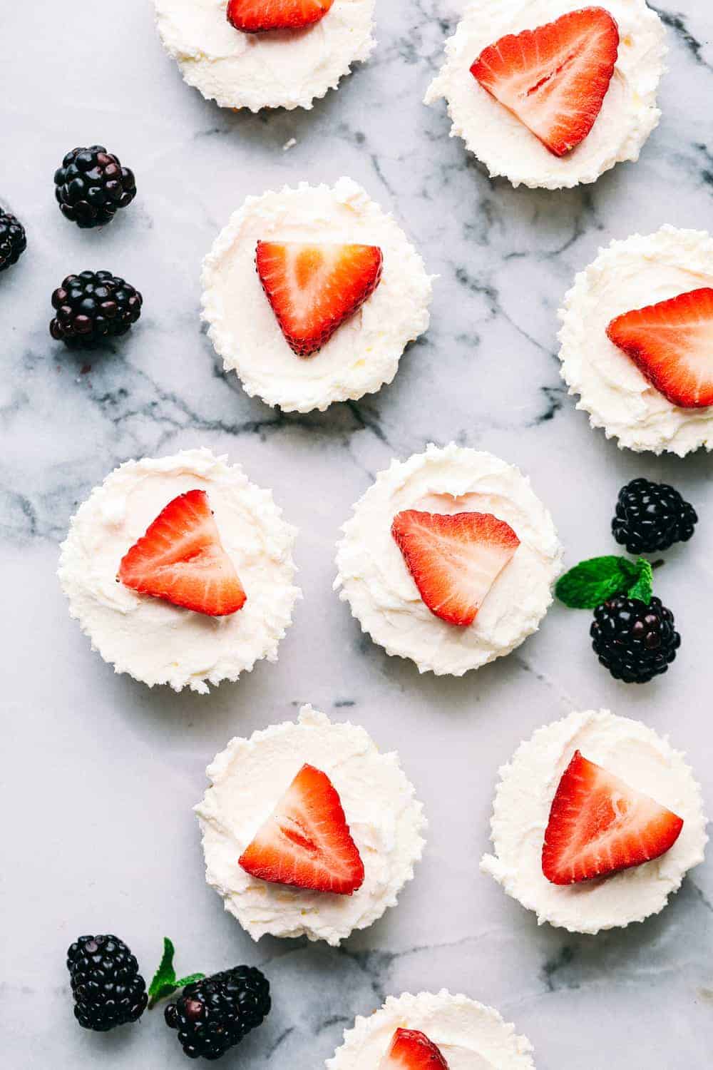 Skinny mini cheesecake bites on a marble counter with blackberries around them.