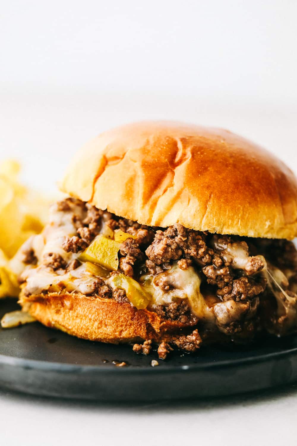 Philly cheese steak sloppy joes on a black plate. 