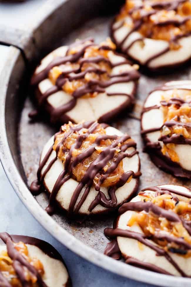 Samoa thumbprint cookies in a cooking tin with chocolate drizzled on top.