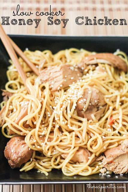 Slow cooker honey soy chicken in noodles with chopsticks and seasoned with sesame seeds all in a black bowl.