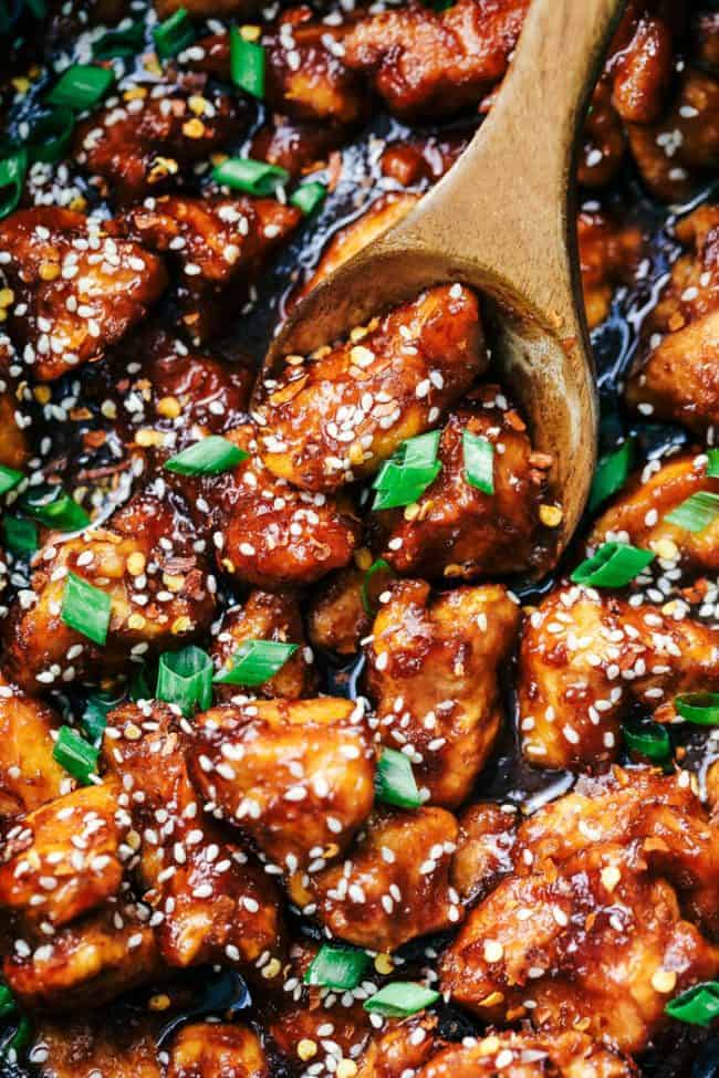 Slow Cooker General Tso's Chicken is a super easy meal with an amazing sweet and savory sauce with a little bit of heat! This is way better than takeout! Slow Cooker General Tso's Chicken with a wooden spoon.