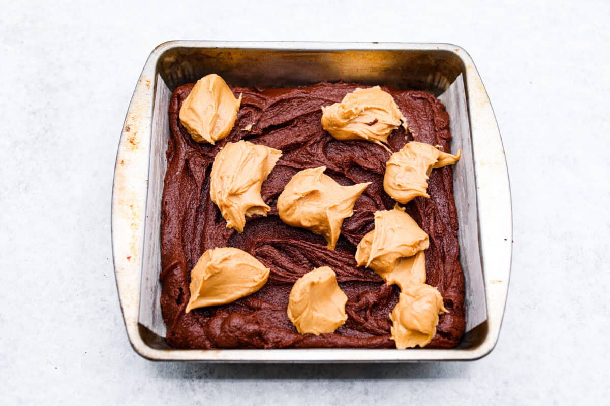 Seventh photo of the peanut butter mixture dolloped on top of the brownie batter.