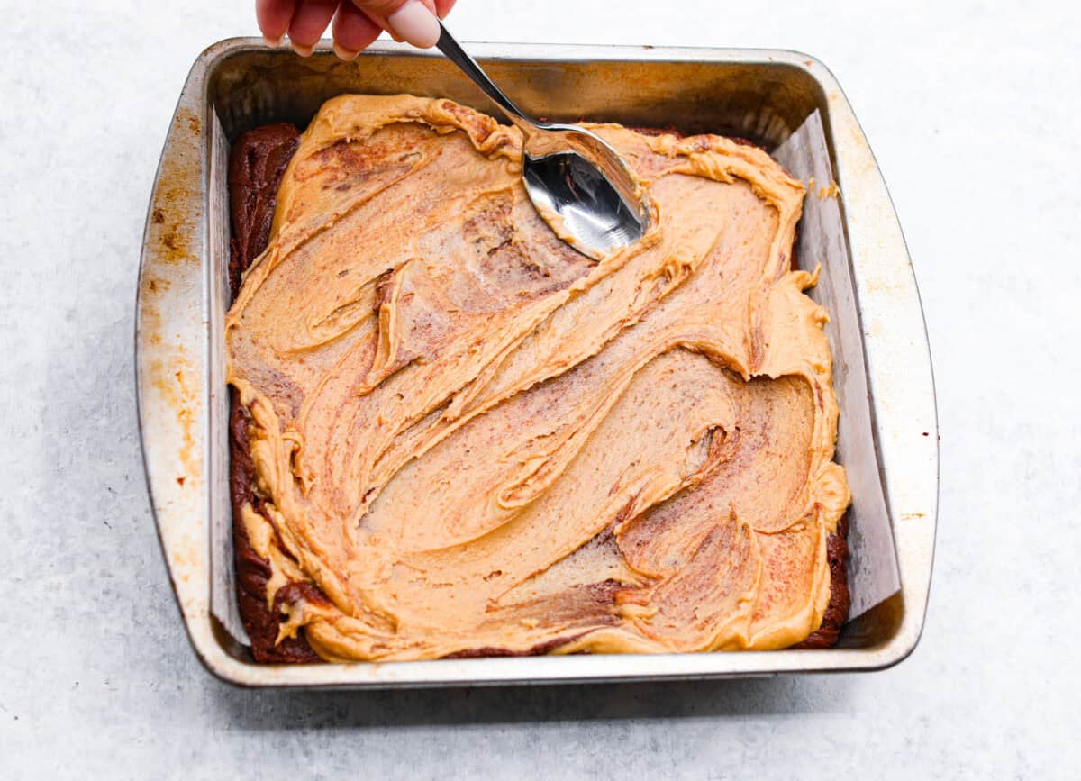 Eighth photo of the peanut butter mixture being swirled into the brownie batter.