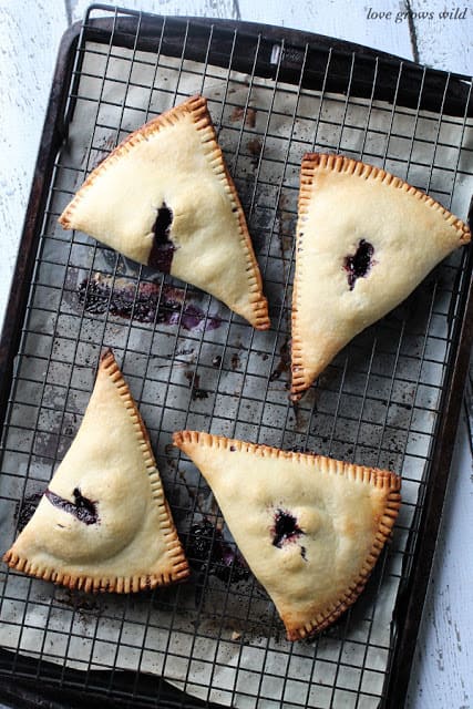 Blueberries and Cream Hand Pies on a cooling rack by LoveGrowsWild.com for The Recipe Critic