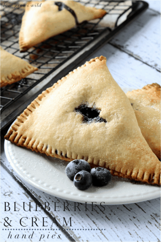 Blueberries and cream hand pies on a white plate.