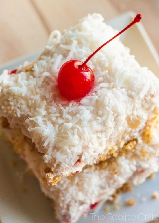 Pina Colada Bars on a white plate with a cherry on top.
