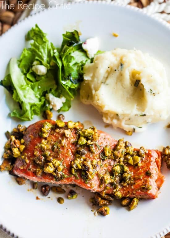 Pistachio Salmon on a white plate with a salad and mashed potatoes.
