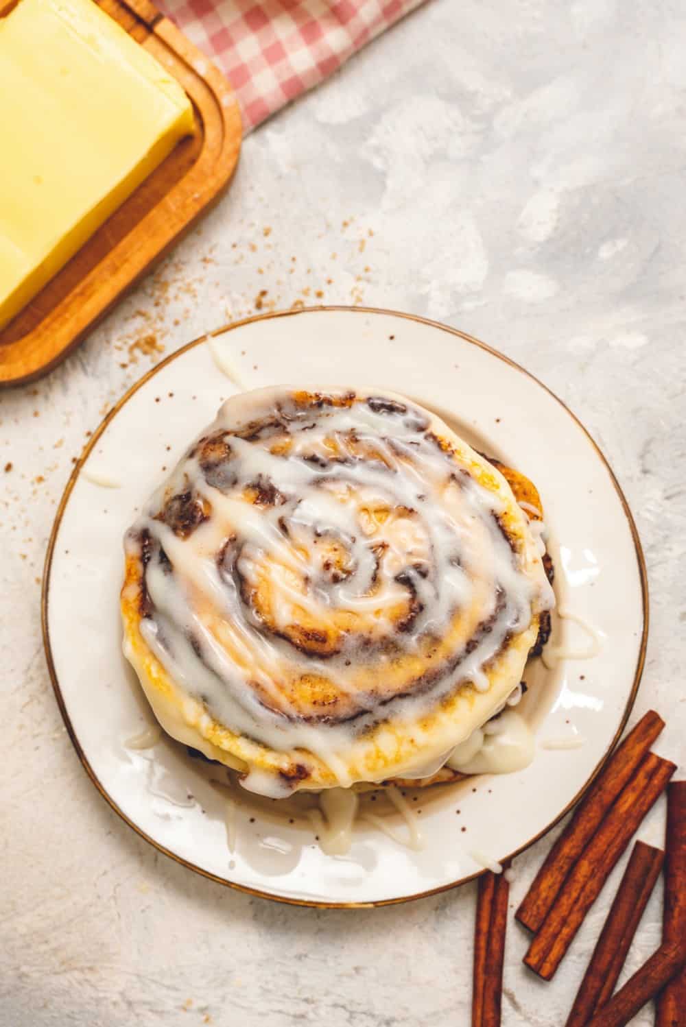 Cinnamon roll pancakes stacked on top of each other with cream cheese glaze drizzled over top.