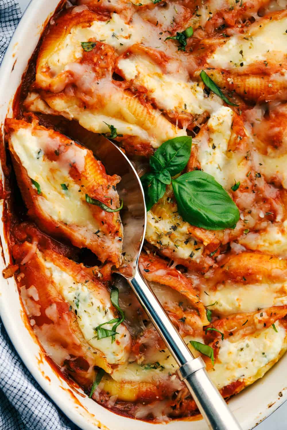 Three cheese stuffed shells baked in a pan with a spoon.