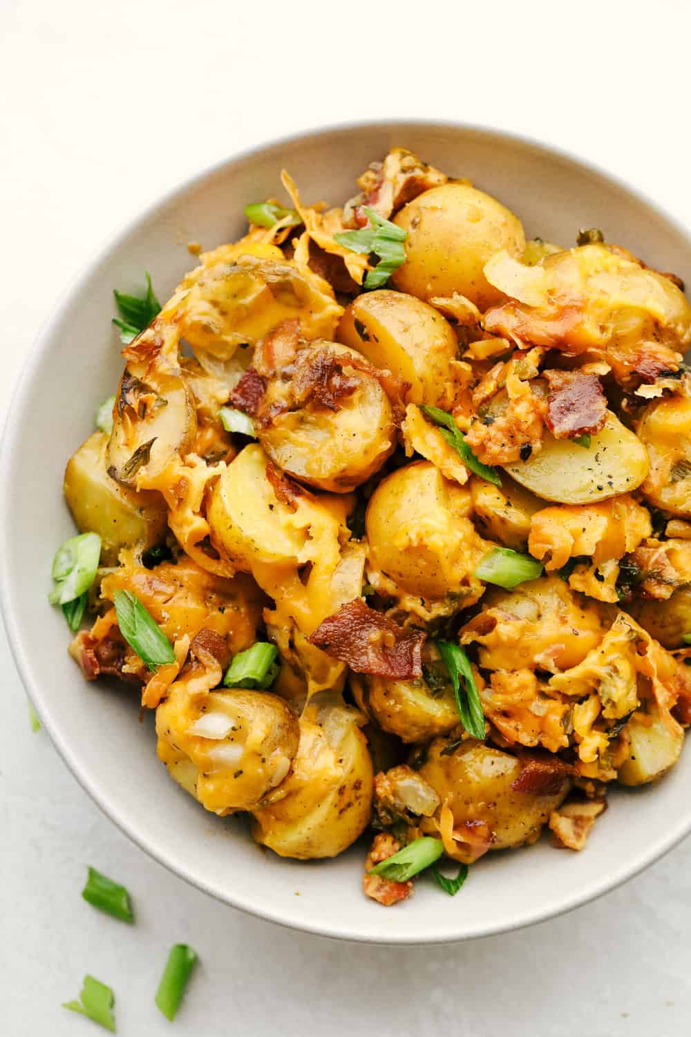 Slow cooker cheesy potatoes in a white bowl. 