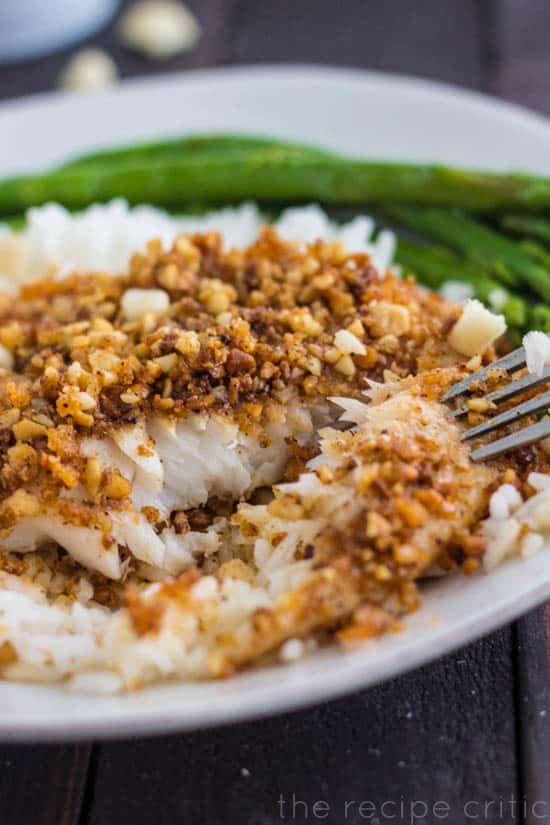 White plate with macadamia crusted talapia and asparagus.