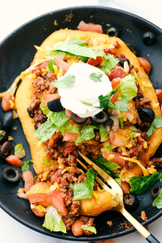 Tacos de navajo con carne molida, lechuga de frijoles al horno, aceitunas y tomates encima con una cucharada de crema agria. 