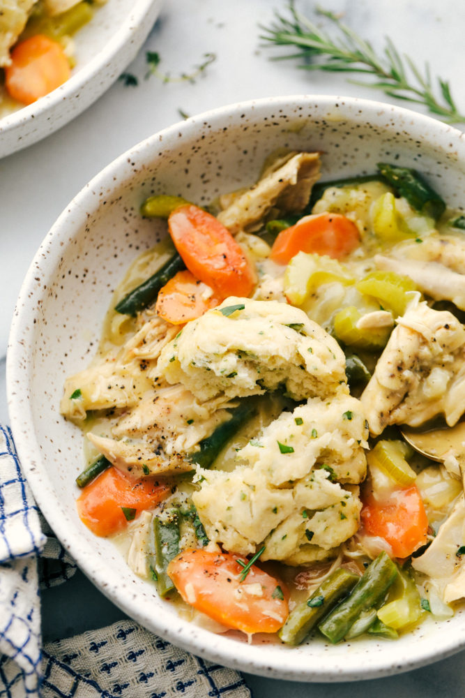 Chicken and dumplings in a bowl with carrots and asparagus. 