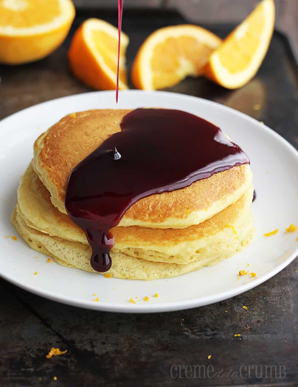 Orange Buttermilk Pancakes drizzled with syrup on a white plate.