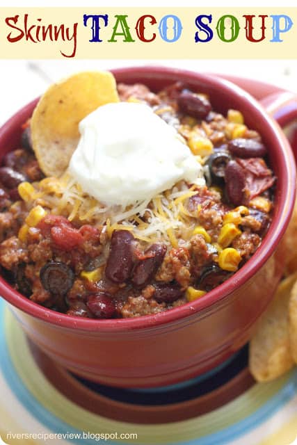 Skinny Taco soup in a red bowl with a dollop of sour cream and tortilla chip.