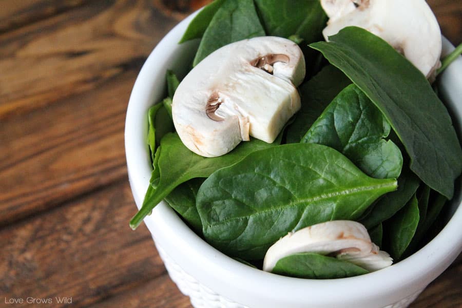 Baby spinach and sliced mushrooms in a white dish by Love Grows Wild for The Recipe Critic