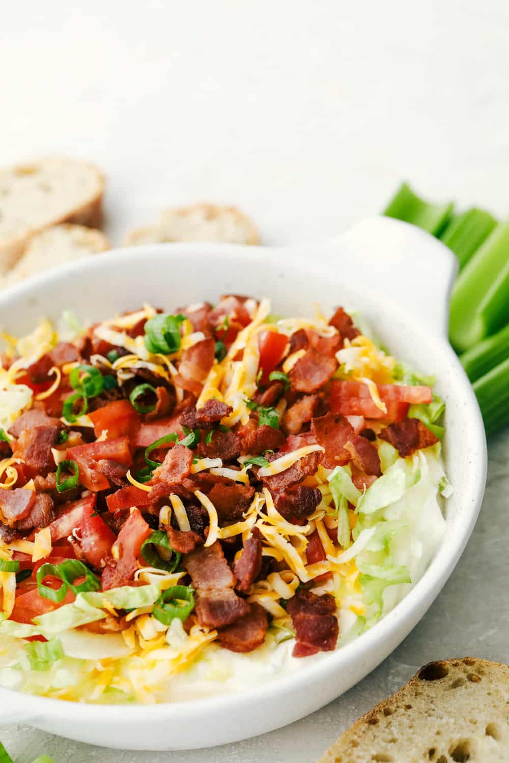 The finished BLT dip in a white bowl with options for dipping. 