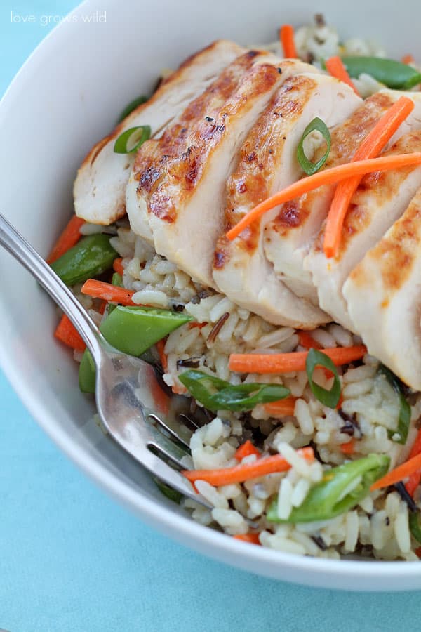Close up of Grilled Citrus Chicken Rice Bowl in a white bowl with a metal fork. 