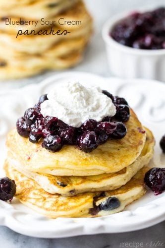 Blueberry Sour Cream Pancakes stacked on white plates. 