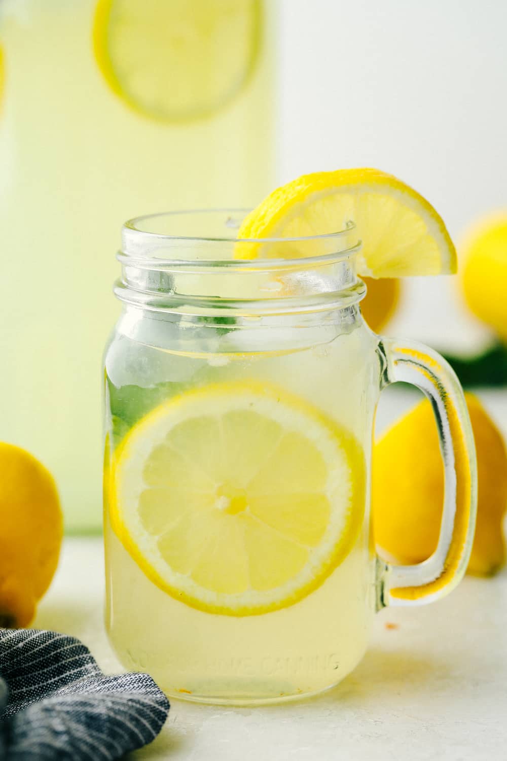 Lemonade ready to drink in a clear mason jar with lemons and mint garnish. 