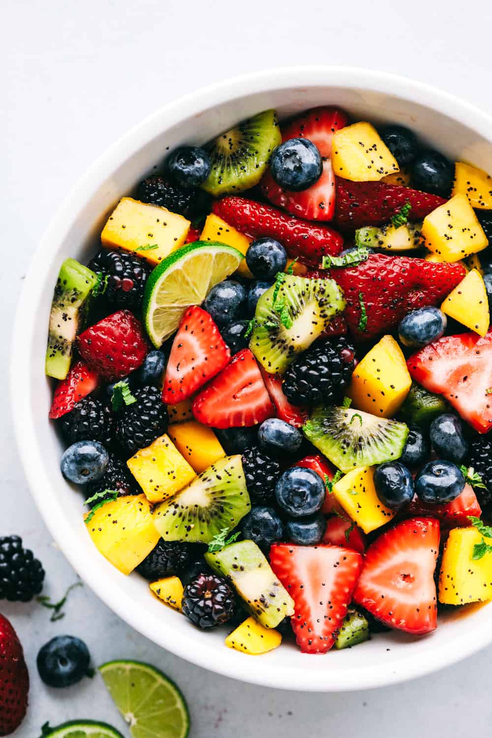 Fruit salad in a bowl drizzled with honey lime poppy seed dressing.