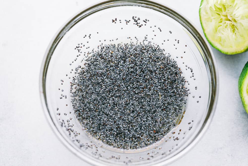 A bowl of poppy seeds mixed with honey and lime ready to drizzle on the fruit salad. 